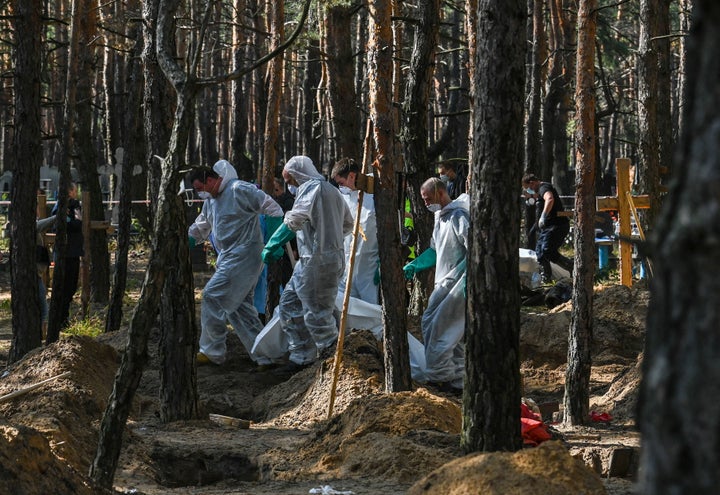 Forensic technicians investigate a mass grave site in a forest near Izium, in eastern Ukraine, on September 18, 2022.