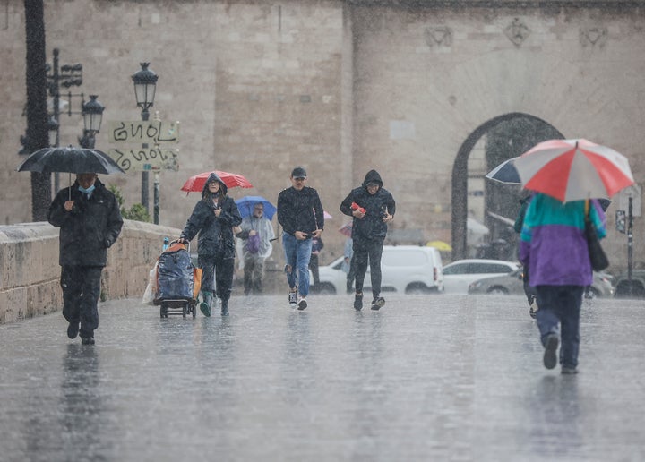 Varias personas, bajo una lluvia fuerte en Valencia.