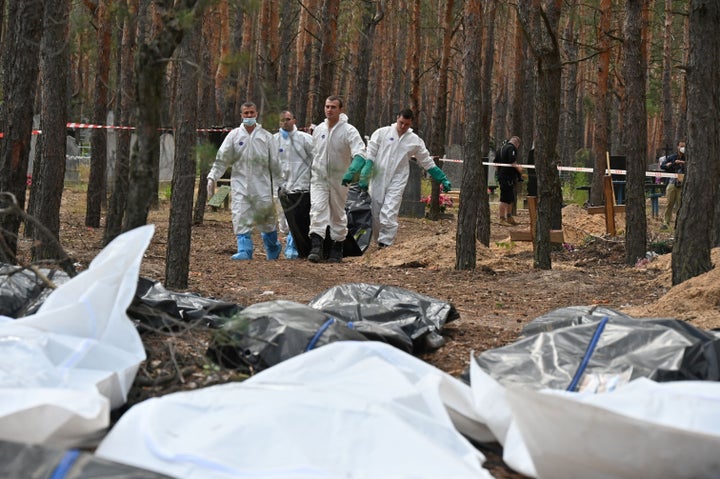 Forenses levantando cadáveres en el bosque de Izium.