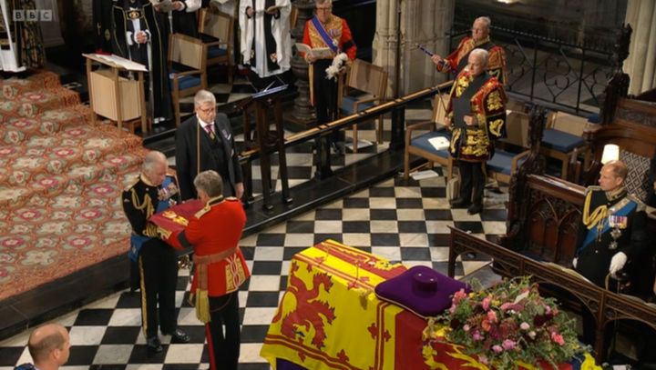 Charles accepting the flag which will be buried with the Queen
