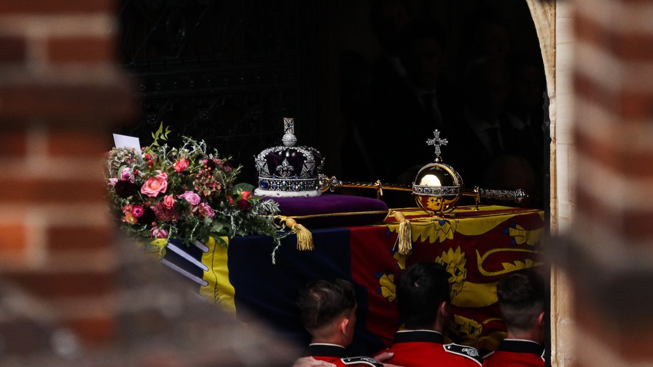 The coffin of Queen Elizabeth II, draped in a Royal Standard and adorned with the Imperial State Crown and the Sovereign's orb and sceptre, enters St George's Chapel inside Windsor Castle.