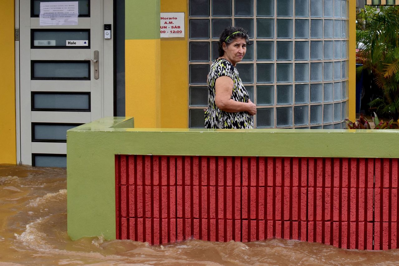 A woman stands outside a flooded house in Salinas, Puerto Rico, on Monday.