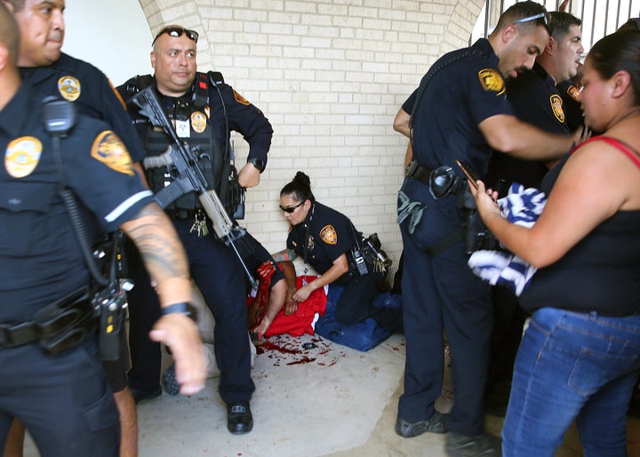 Police tend to a man after he shoved his first through a window in an effort to gain entry to Thomas Jefferson High School on Tuesday.