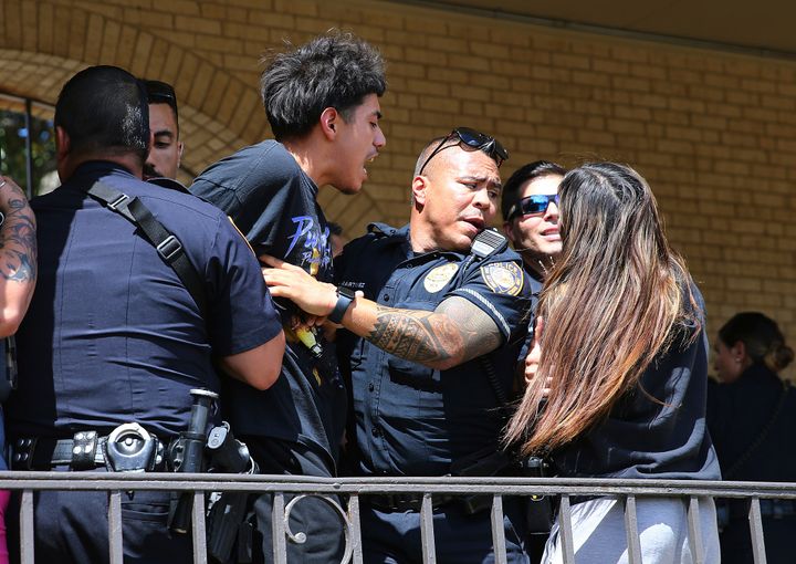 A man is handcuffed as chaos ensues outside Thomas Jefferson High School on Tuesday.