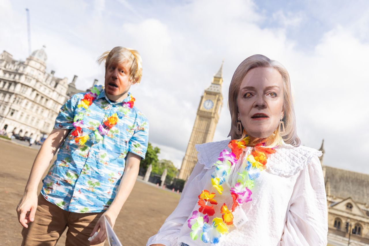 Campaigners wearing masks of Boris Johnson and Liz Truss, take part in a Labour party stunt in Parliament Square, Westminster.