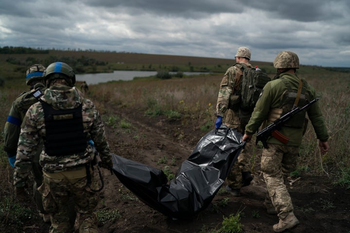 Ukrainian National Guard soldiers carry a bag containing the bodies of Ukrainian soldiers near the border with Russia in the Kharkiv region of Ukraine on September 19, 2022.