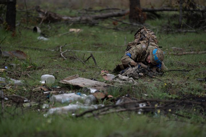 A Ukrainian serviceman looks for booby traps as he checks the site where a body of a Ukrainian soldier was found inside an armored vehicle in an area near the border with Russia, in Kharkiv region, Ukraine, on Sept. 19, 2022. 