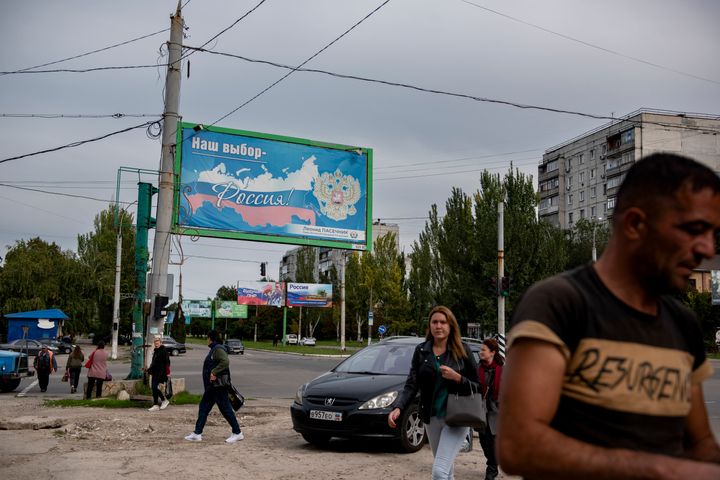 People walk in a street with a billboard that reads: "Our choice - Russia", prior to a referendum in Luhansk, Luhansk People's Republic controlled by Russia-backed separatists, eastern Ukraine, on Sept. 22, 2022. 