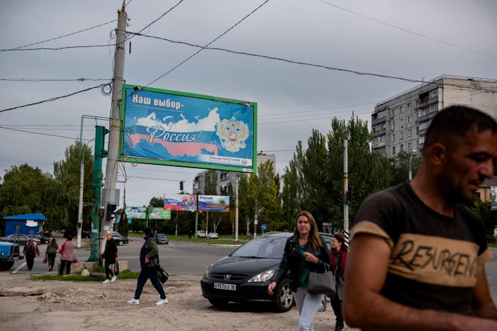 People walk in a street with a billboard that reads: "Our choice - Russia", prior to a referendum in Luhansk, Luhansk People's Republic controlled by Russia-backed separatists, eastern Ukraine, on Sept. 22, 2022.