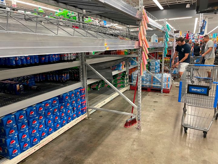 Shoppers take what's left of water on a Walmart store's shelves in Tampa, Florida, on Sunday.
