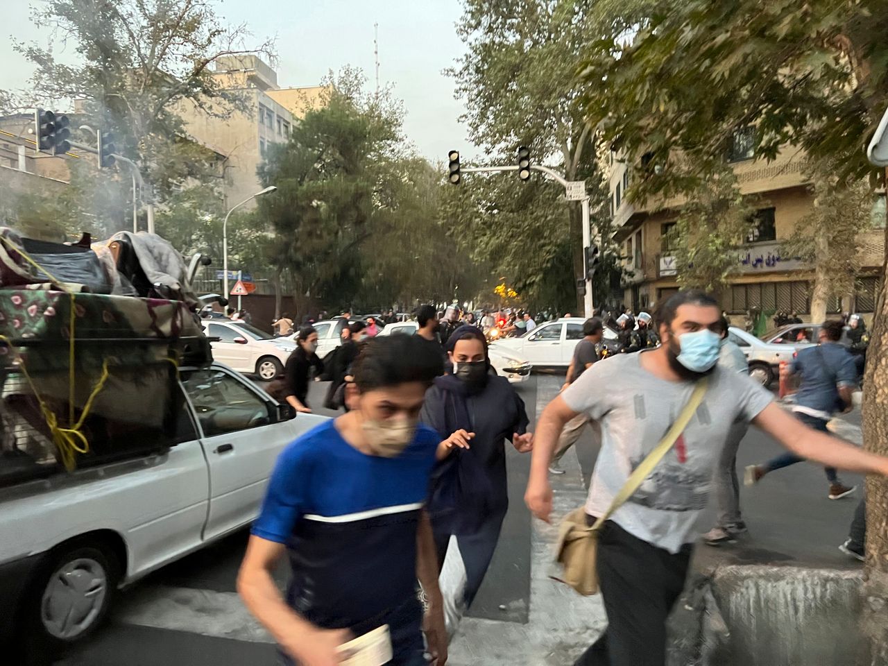 In this Monday, Sept. 19, photo taken by an individual not employed by The Associated Press and obtained by the AP outside Iran, people run away from anti-riot police during a protest over the death of a young woman who had been detained for violating the country's conservative dress code, in downtown Tehran.