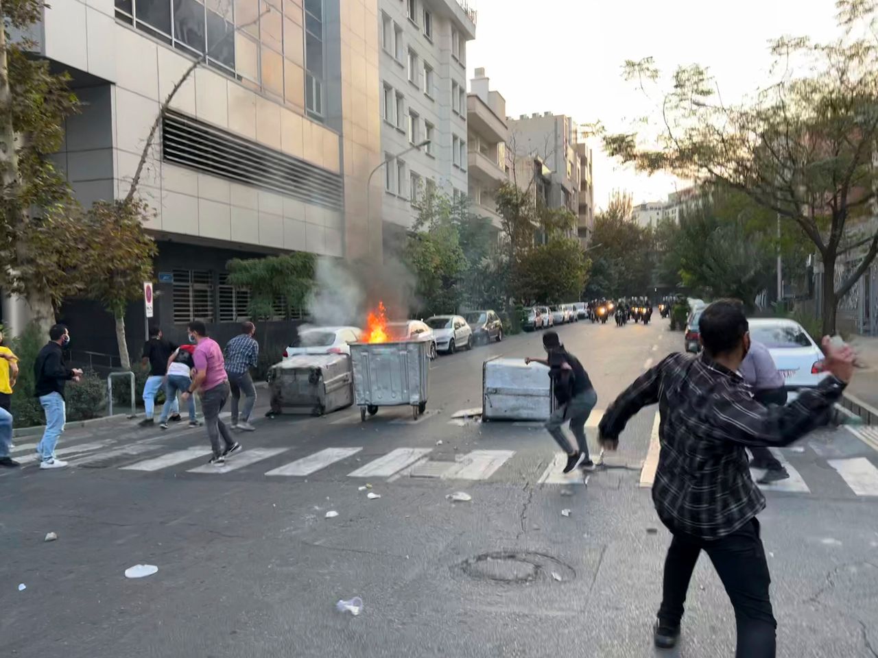 In this Tuesday, Sept. 20, photo taken by an individual not employed by The Associated Press and obtained by the AP outside Iran, protesters throw stones at anti-riot police during a protest over the death of a young woman who had been detained for violating the country's conservative dress code, in downtown Tehran.