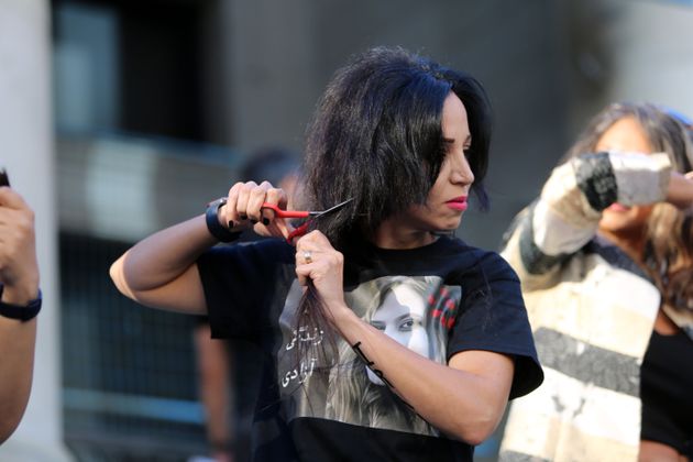 アミニさん死に抗議するデモに参加し、カナダバンクーバー・アートギャラリーの外で髪を切る女性（2022年9月25日）