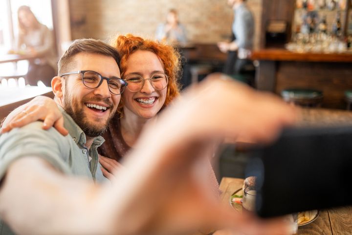 Young couple taking a selfie while eating at a restaurant