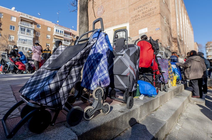 Varias personas hacen cola para recibir alimentos de la Fundación Madrina, en la plaza de San Amaro, en Madrid.