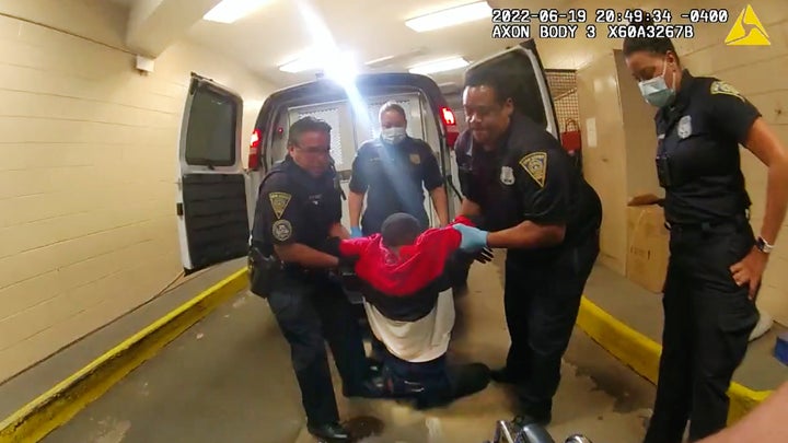 A still from police body camera video shows Cox being pulled from the back of a police van and then placed in a wheelchair after being detained by New Haven Police. 