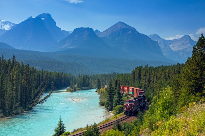 A Canadian Pacific Railway freight train follows the Bow River at Morant's Curve in Banff National Park, Canada.