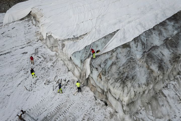 Ειδικοί εργάζονται πάνω σε έναν μουσαμά που καλύπτει τον παγετώνα Corvatsch, κοντά στο Samedan, στην Ελβετία, Δευτέρα, 5 Σεπτεμβρίου 2022.