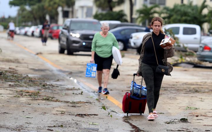 Residents leave with their belongings Wednesday after an apparent overnight tornado spawned by Hurricane Ian hit the Kings Point 55+ community in Delray Beach.