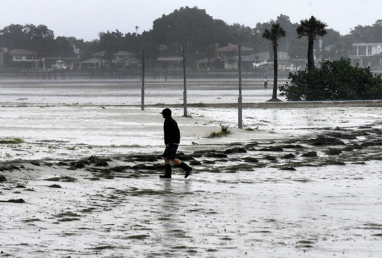 A local resident walks in the rain and wind at a bay in St. Petersburg as Hurricane Ian approaches Wednesday.