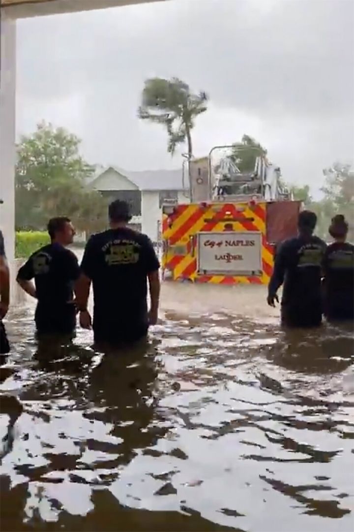 Firefighters look out at a firetruck stopped amid water from a storm surge caused by Hurricane Ian.