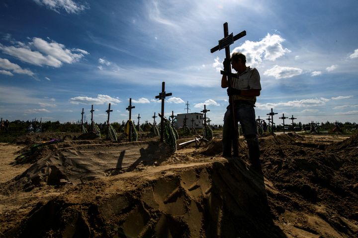 Un voluntario coloca una cruz en un cementerio con cuerpos sin identificar en Bucha.
