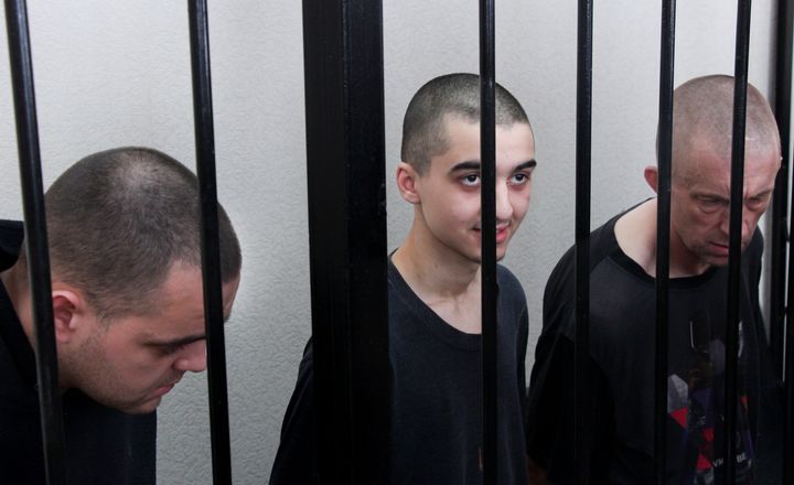 O Σον Πίνερ, o Άιντεν Άσλιν και ο Μαροκινός Σαντούν Μπραχίμ, πίσω από τα κάγκελα μιας αίθουσας δικαστηρίου στο Ντονέτσκ, στην περιοχή που βρίσκεται υπό έλεγχο της κυβέρνησης της Λαϊκής Δημοκρατίας του Ντονέτσκ, ανατολική Ουκρανία, Πέμπτη, 9 Ιουνίου 2022. Μετά από τη δίκη καταδικάστηκαν σε θάνατο.