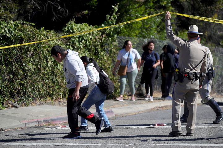 A California Highway Patrol officer lifts police tape to let parents and students leave a cordoned off area following a shooting at a school campus in Oakland, California on Wednesday. 