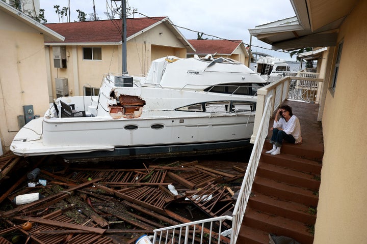 Brenda Brennan sits next to a boat that pushed against her Fort Meyers apartment when Hurricane Ian passed through the area.