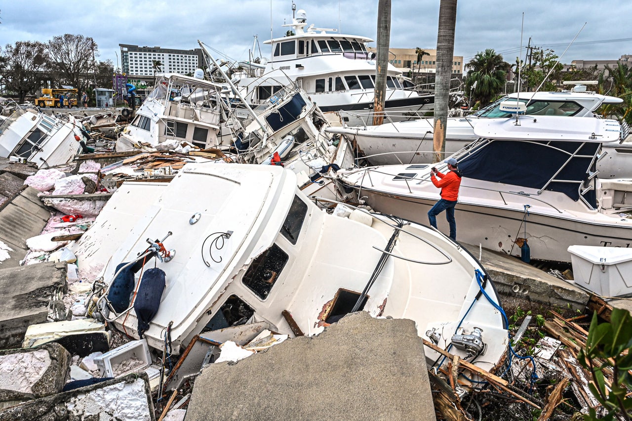 A man takes photos of boats wrecked by Hurricane Ian in Fort Myers on Thursday.