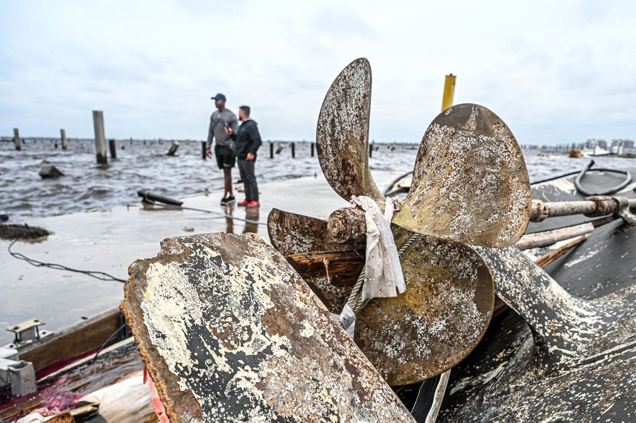 Residents inspect damage to a marina as boats are partially submerged in the aftermath of Hurricane Ian in Fort Myers, on Sept. 29.