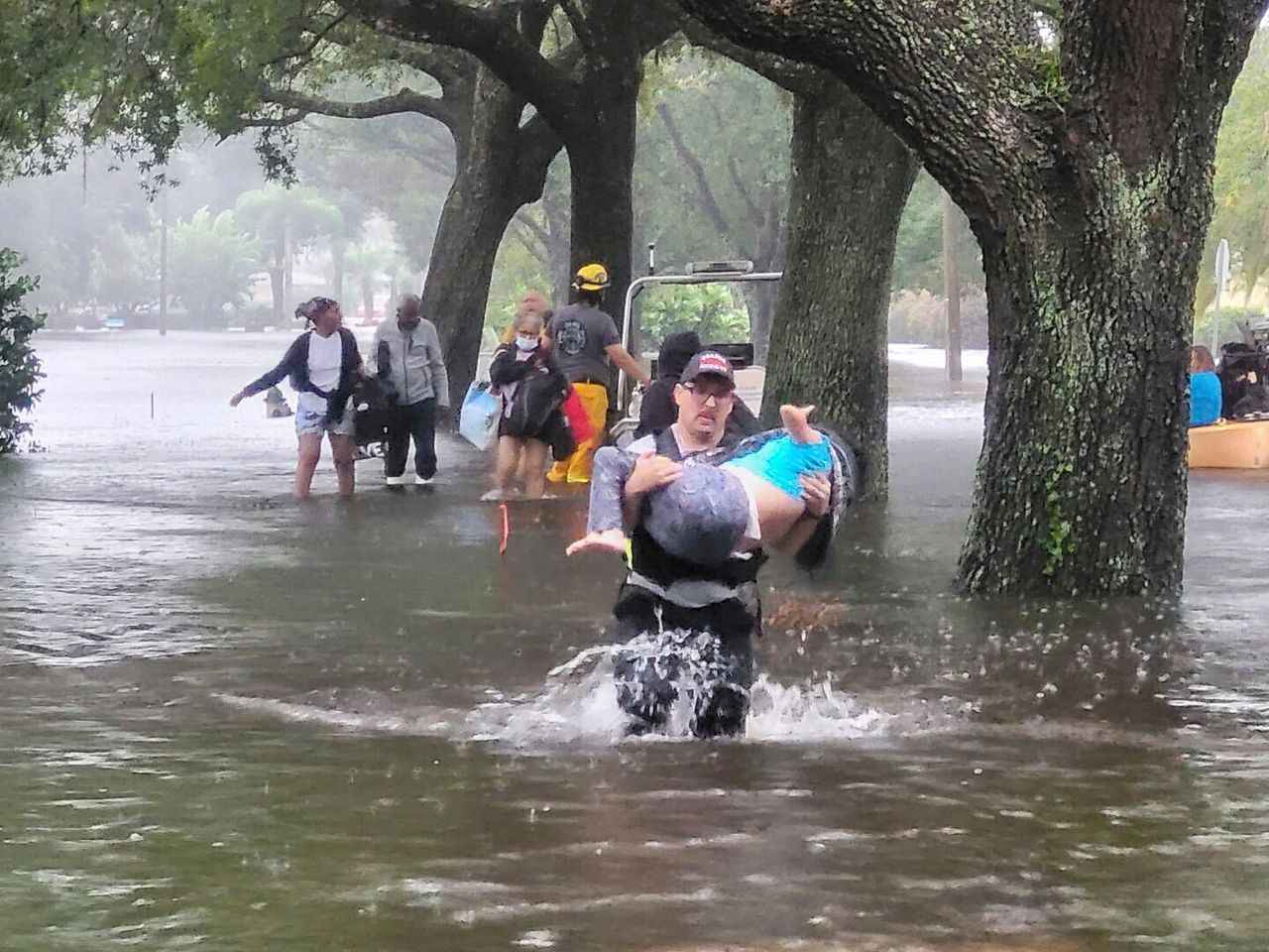 In this photo, provided by the Orange County Fire Rescue Public Information Agency, firefighters help people stranded by Hurricane Ian early Thursday.