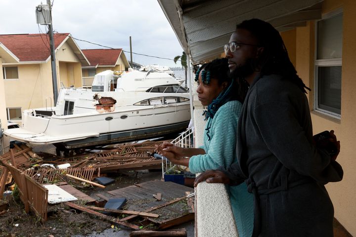 Frankie Romulus (and Kendrick Romulus stand outside of their apartment next to a boat that floated into their apartment complex in Fort Myers.