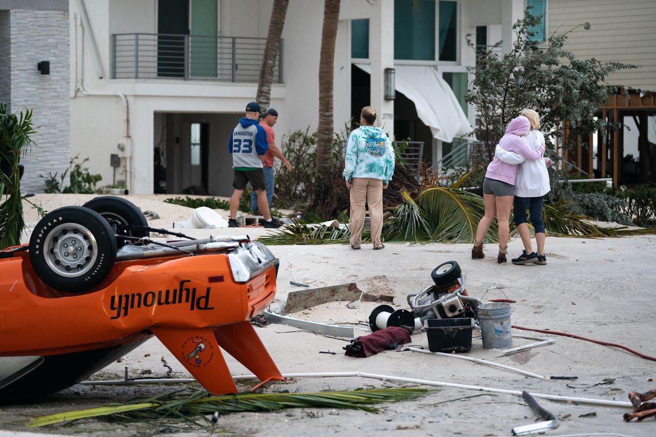 People embrace as they survey property damage in Bonita Springs on Sept. 29. 
