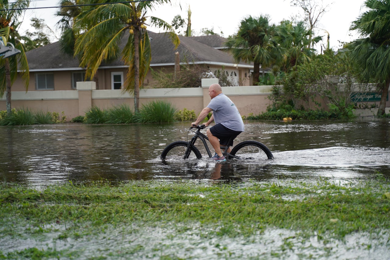 A man tries to ride a bicycle in flooding in Fort Myers on September 29.