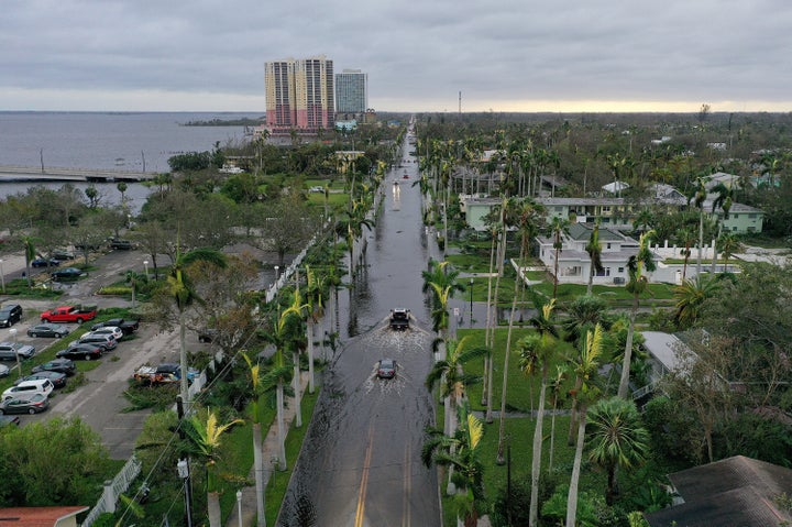 Vehicles make their way through a flooded area of Fort Myers after Hurricane Ian passed through the area.