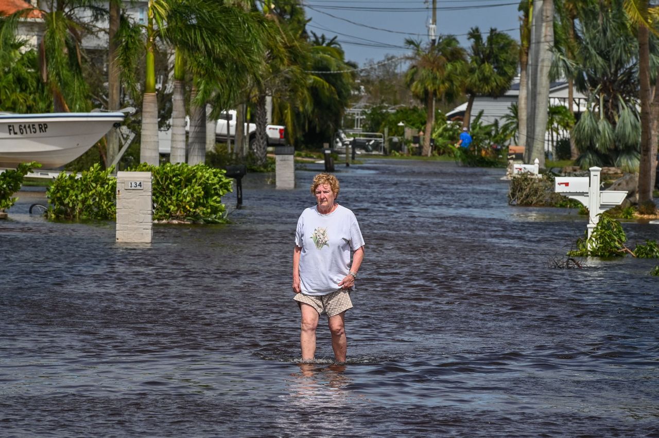 A woman walks through her Fort Myers neighborhood Thursday on a flooded street in the aftermath of Hurricane Ian.