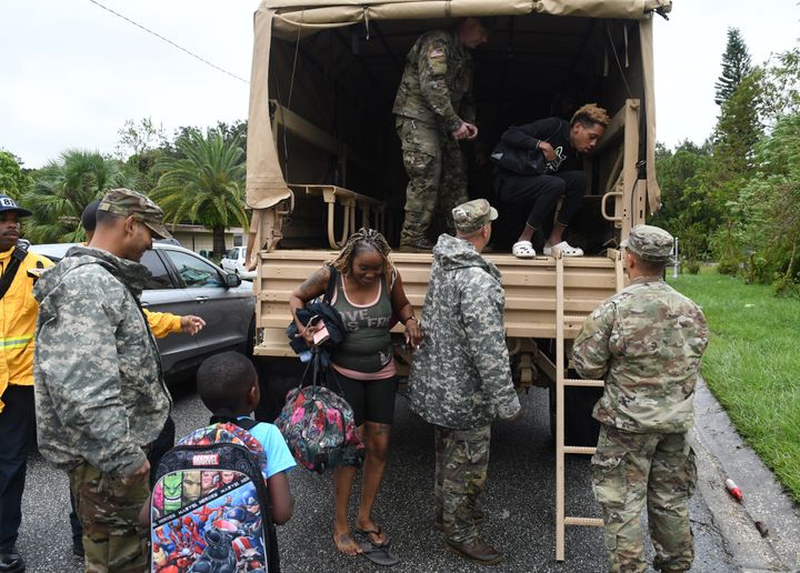 Residents exit a military vehicle after being rescued from their flooded homes by members of the Florida National Guard. 