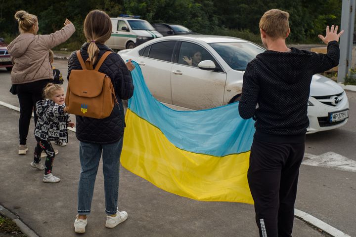 Ukrainians, who earlier had left occupied territories, are holding Ukrainian flag and waving to welcome their friends who has just arrived to the Zaporizhzhia Center for IDPs, Ukraine, on Sept. 28, 2022. 
