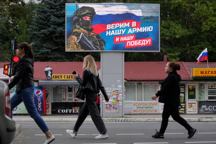 Un grupo de ciudadanos pasea el pasado martes por una calle de Luhansk, en Lugansk, ante un cartel con un soldado ruso que dice: "Creemos en nuestro ejército y en nuestra victoria".