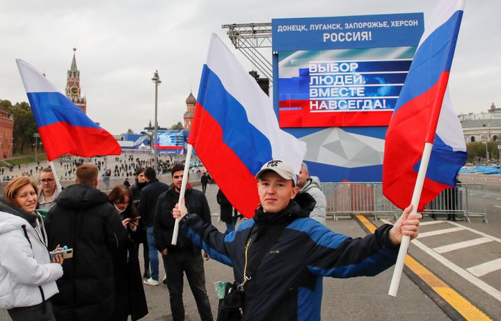 Ciudadanos rusos festejan la anexión mientras siguen el discurso de Putin en pantallas gigantes instaladas ante el Kremlin y la Plaza Roja.