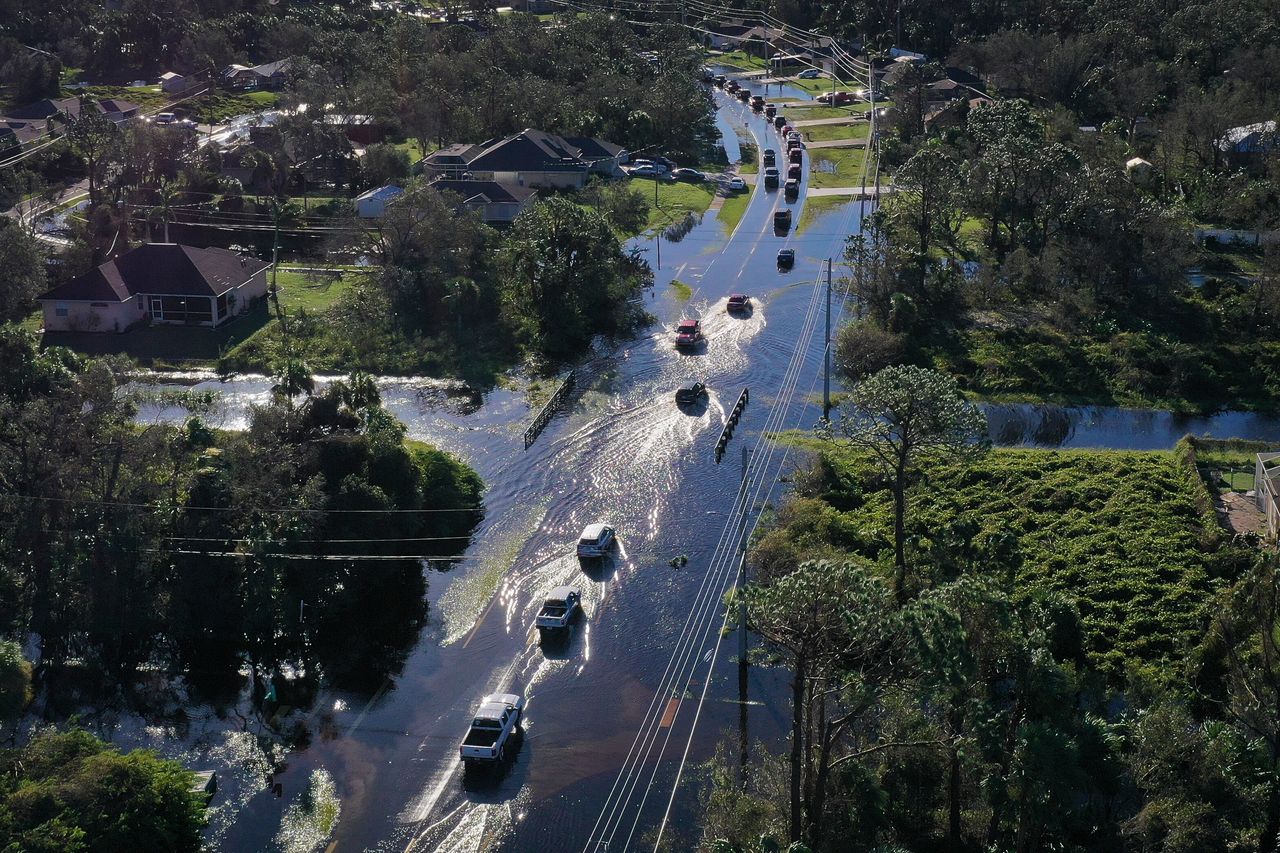 Vehicles drive through standing water left in the wake of Hurricane Ian on Sept. 30 in Port Charlotte. 