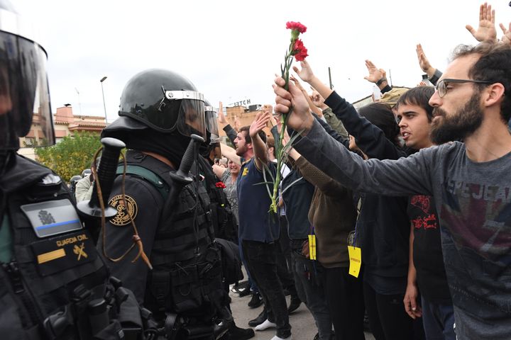 Un grupo de ciudadanos catalanes entrega flores a la Policía mientras intentan votar en el 1-0