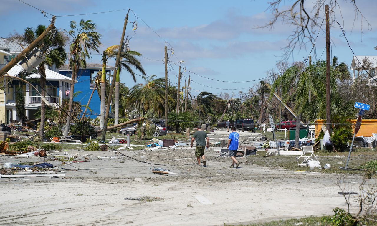 People walk down a storm-littered road in Fort Myers Beach on Sept. 29.