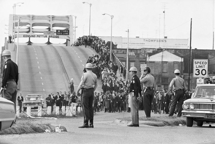 State troopers watch as civil rights marchers cross the Edmund Pettus Bridge over the Alabama River in Selma, Alabama two days before troopers used excessive force driving marchers back across the bridge, killing one protester.