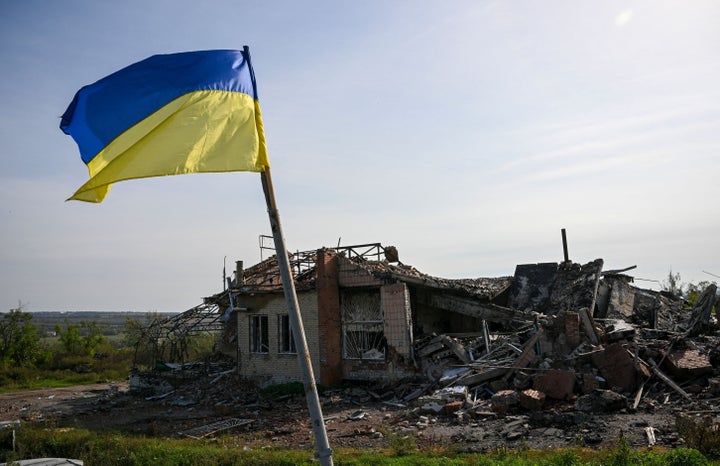 Un bandera ucraniana frente a un edificio destruido.