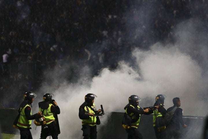 Police officers fire tear gas during clashes between fans at a soccer match at Kanjuruhan Stadium in Malang, East Java, Indonesia, Saturday, Oct. 1, 2022. Panic following police actions left over 100 dead, mostly trampled to death, police said Sunday.
