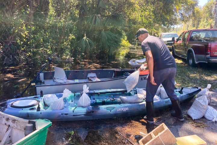 Gabriel Madlang loads sandbags onto his kayak so he can fortify his house on a submerged street in Seminole County, Fla., on Sunday, Oct. 2, 2022. Residents in central Florida donned fishing waders, boots and bug spray and canoed or kayaked to their homes on streets where floodwaters continued rising Sunday despite it being four days since Hurricane Ian tore through the state.