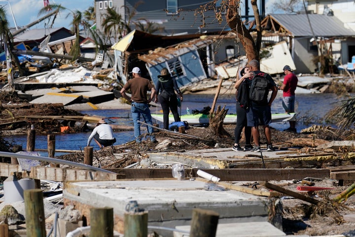 Les gens se tiennent sur le pont détruit vers Pine Island alors qu'ils voient les dégâts à la suite de l'ouragan Ian à Matlacha, en Floride, le dimanche 2 octobre 2022. Le seul pont vers l'île est fortement endommagé, il ne peut donc être atteint que par bateau ou avion.  (AP Photo/Gérald Herbert)