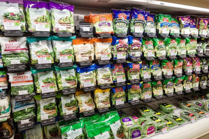 Varias ensaladas de bolsa, en los estantes de un supermercado.